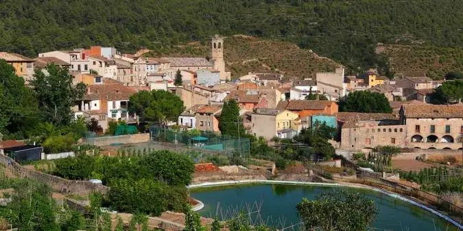 pueblo copons en comarca anoia, vista general con rio, casas, arboles verdes monte